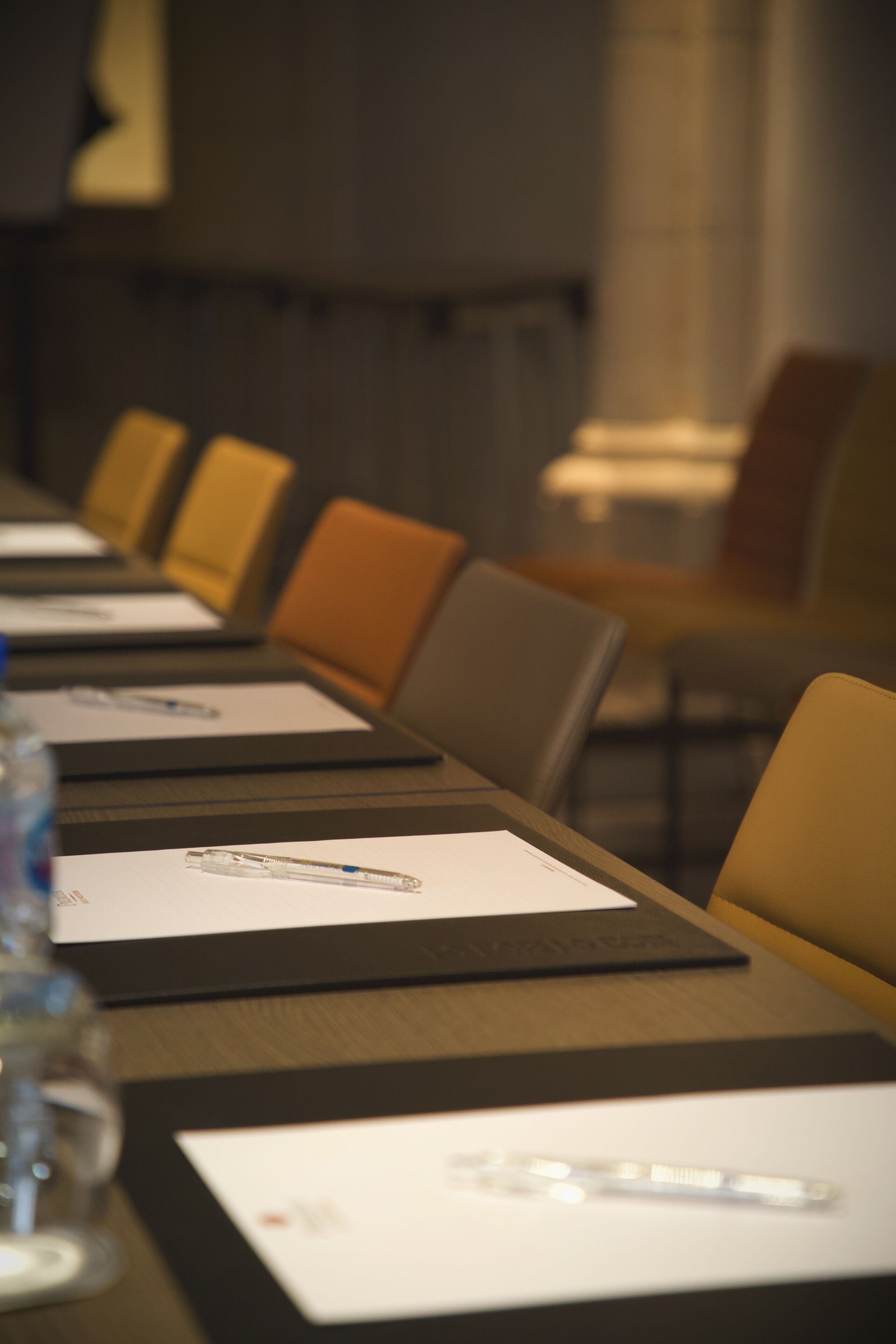 A conference room with a long table, chairs, and documents.