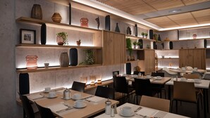 A modern dining area with wooden tables and chairs, shelves with decorative items, and a ceiling with wooden slats. - Best Western Premier Hôtel de la Paix (Reims)