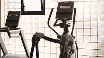 A gym with treadmills and an elliptical machine, a TV screen, and a window with a view.