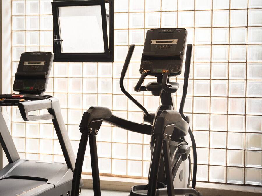 A gym with treadmills and an elliptical machine, a TV screen, and a window with a view.