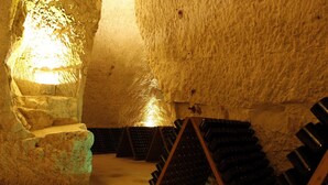 An underground wine cellar with stone walls and wooden racks holding wine bottles. - Best Western Premier Hôtel de la Paix (Reims)