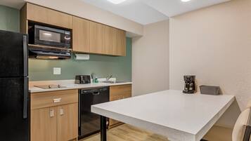 A compact kitchen with wooden cabinets, a microwave, a dishwasher, and a coffee maker.