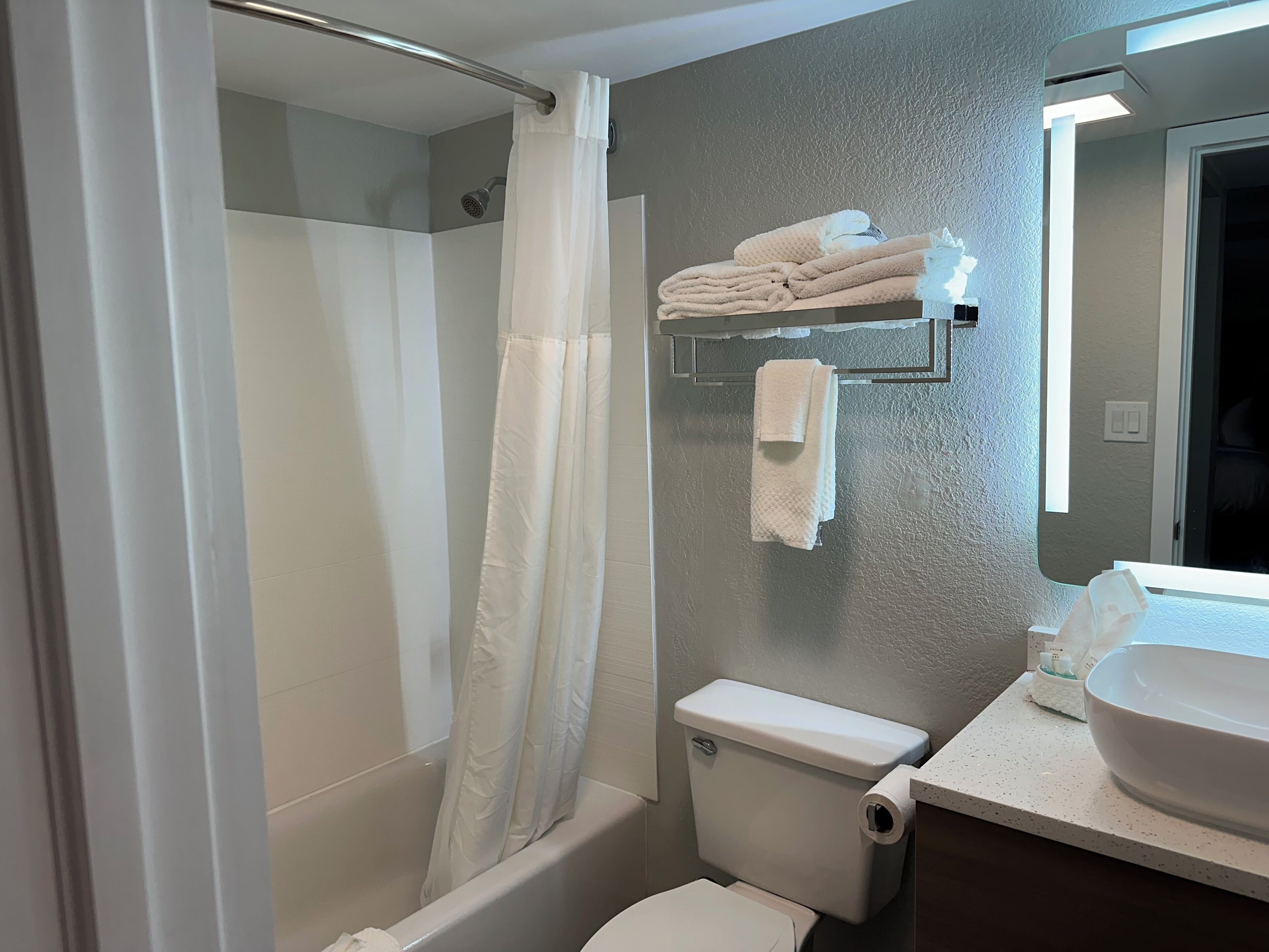 A bathroom with a bathtub, toilet, and a sink with a mirror.