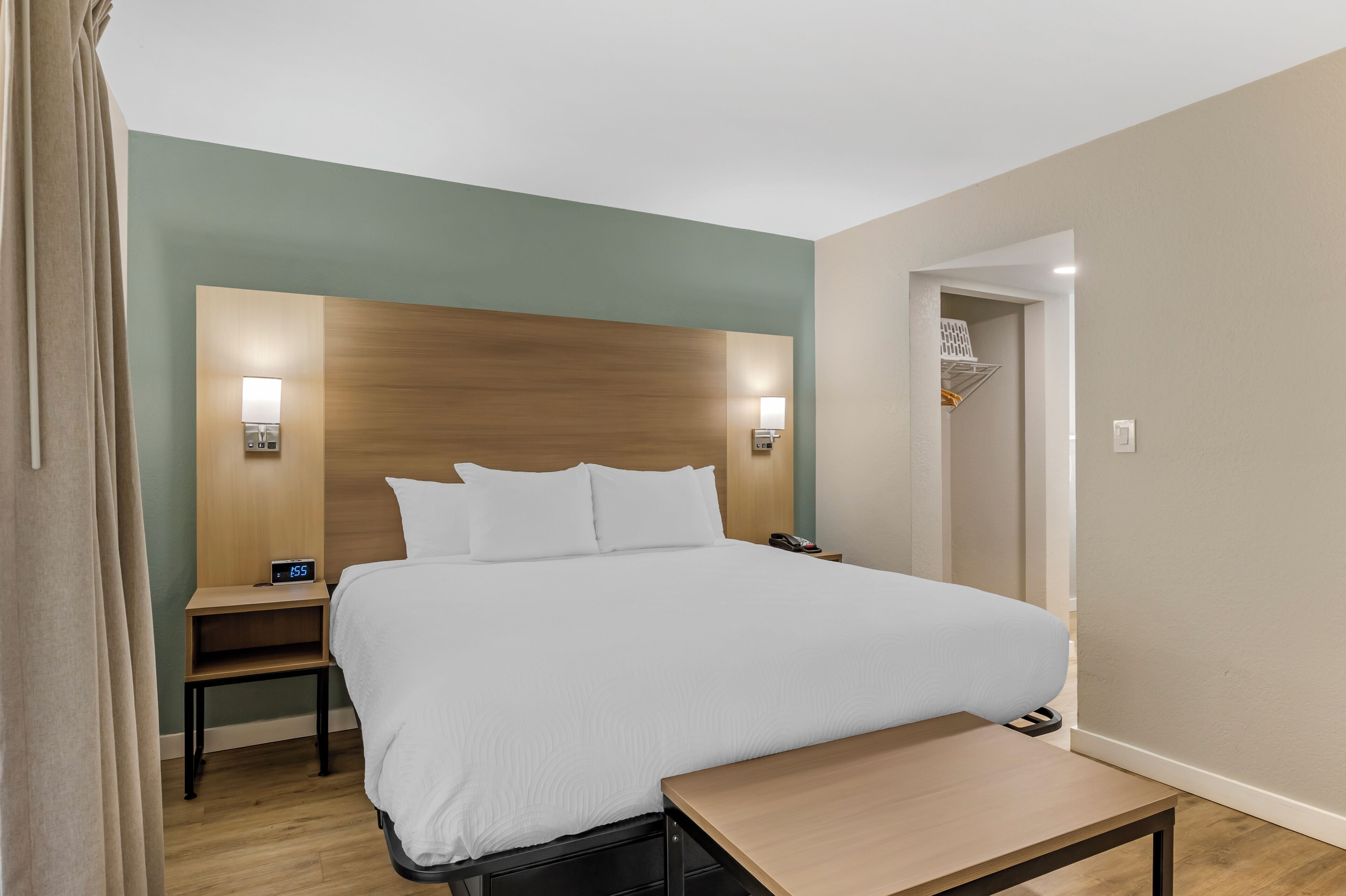 A hotel room with a large bed, bedside tables, a desk, and a wardrobe.