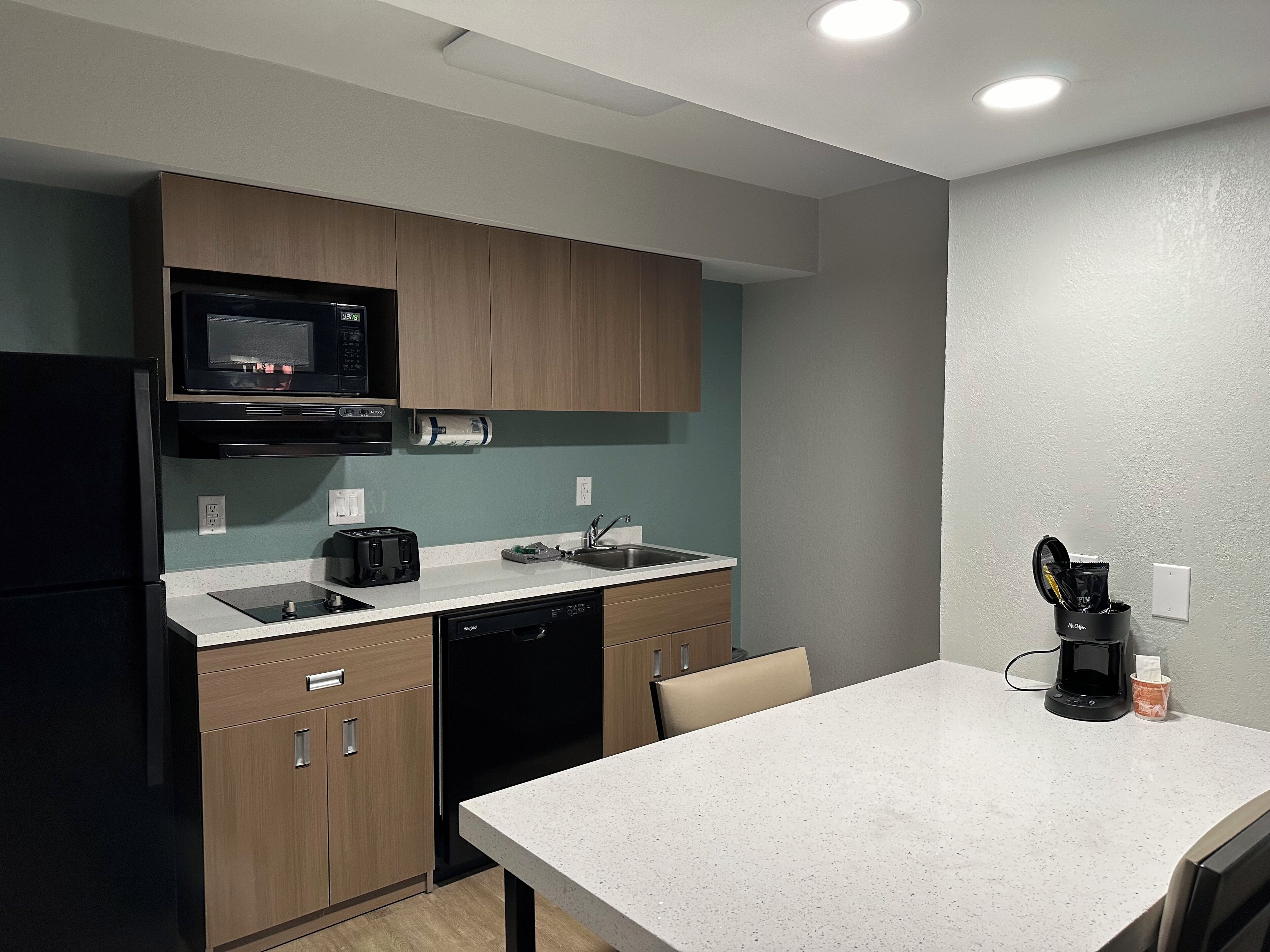 A compact kitchen with a microwave, toaster, sink, and dishwasher.
