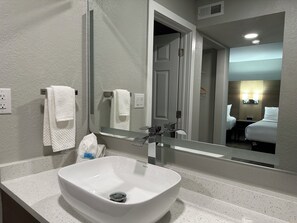 Bathroom features a large mirror above a sink with a single faucet.