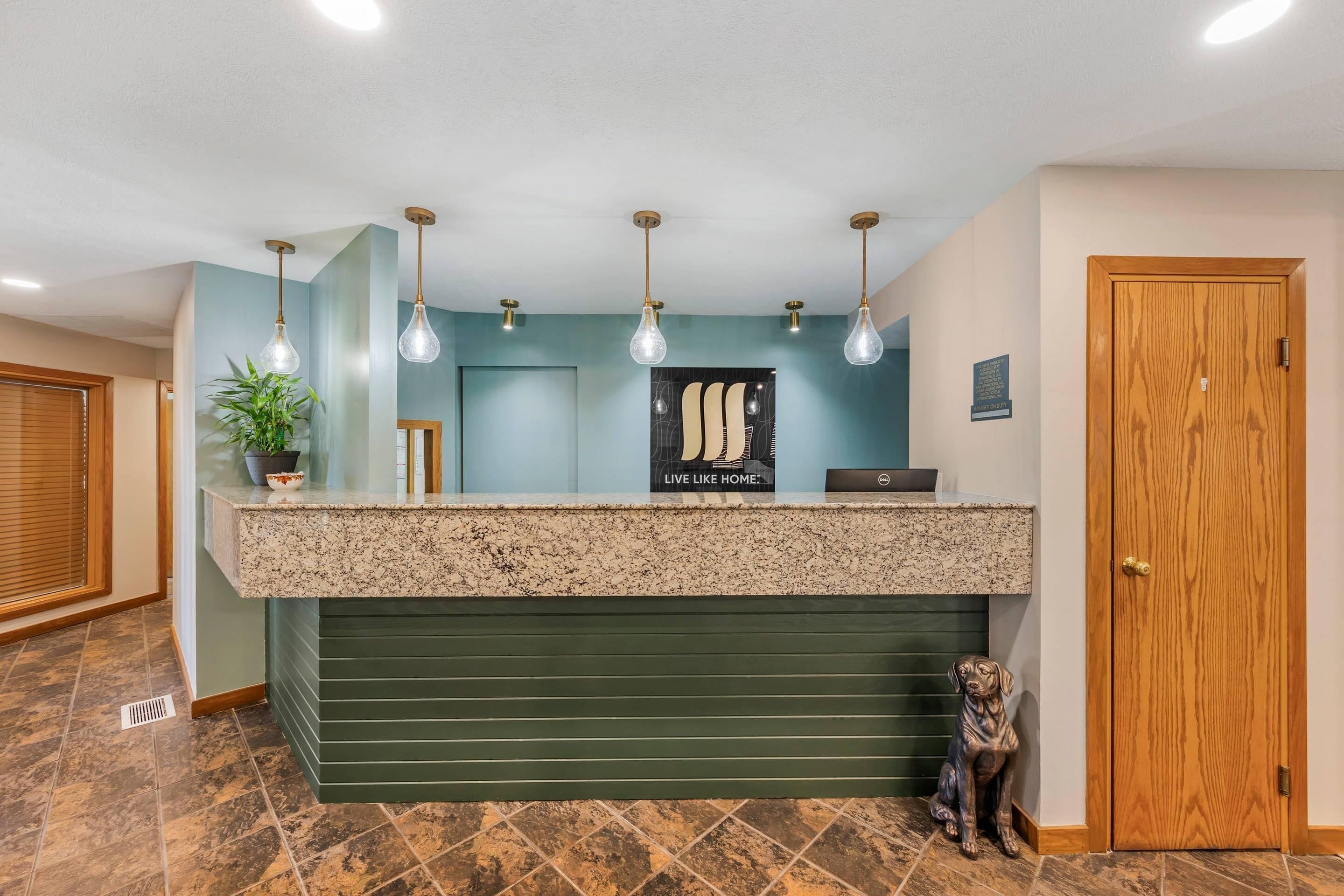 A reception desk with a green counter, a potted plant, and a dog statue.