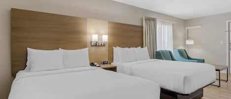 Ein Hotelzimmer mit zwei Betten, einem Nachttisch mit Telefon, Lampe und einem Sessel.