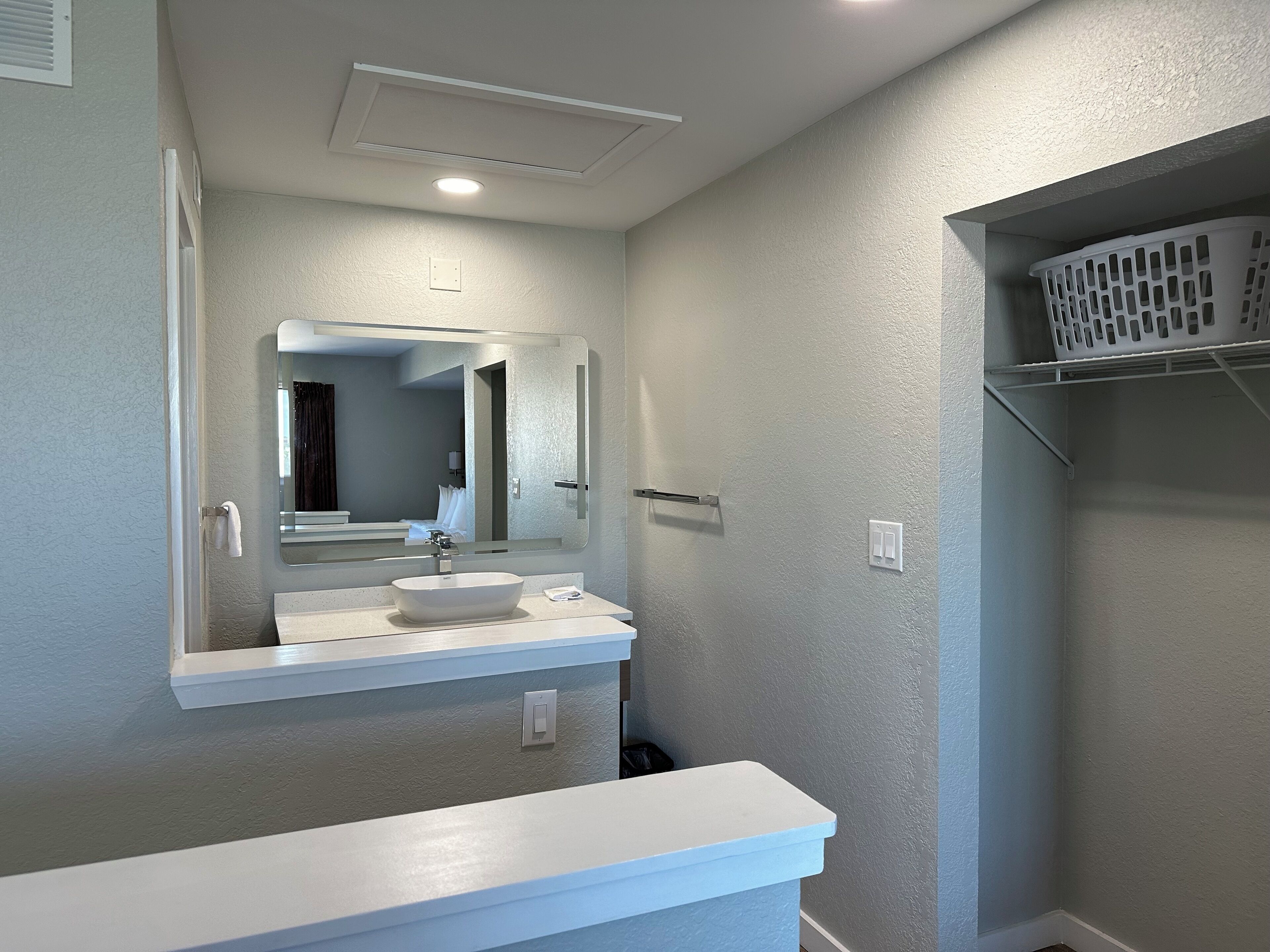Une salle de bain avec un lavabo blanc, un miroir et un luminaire.
