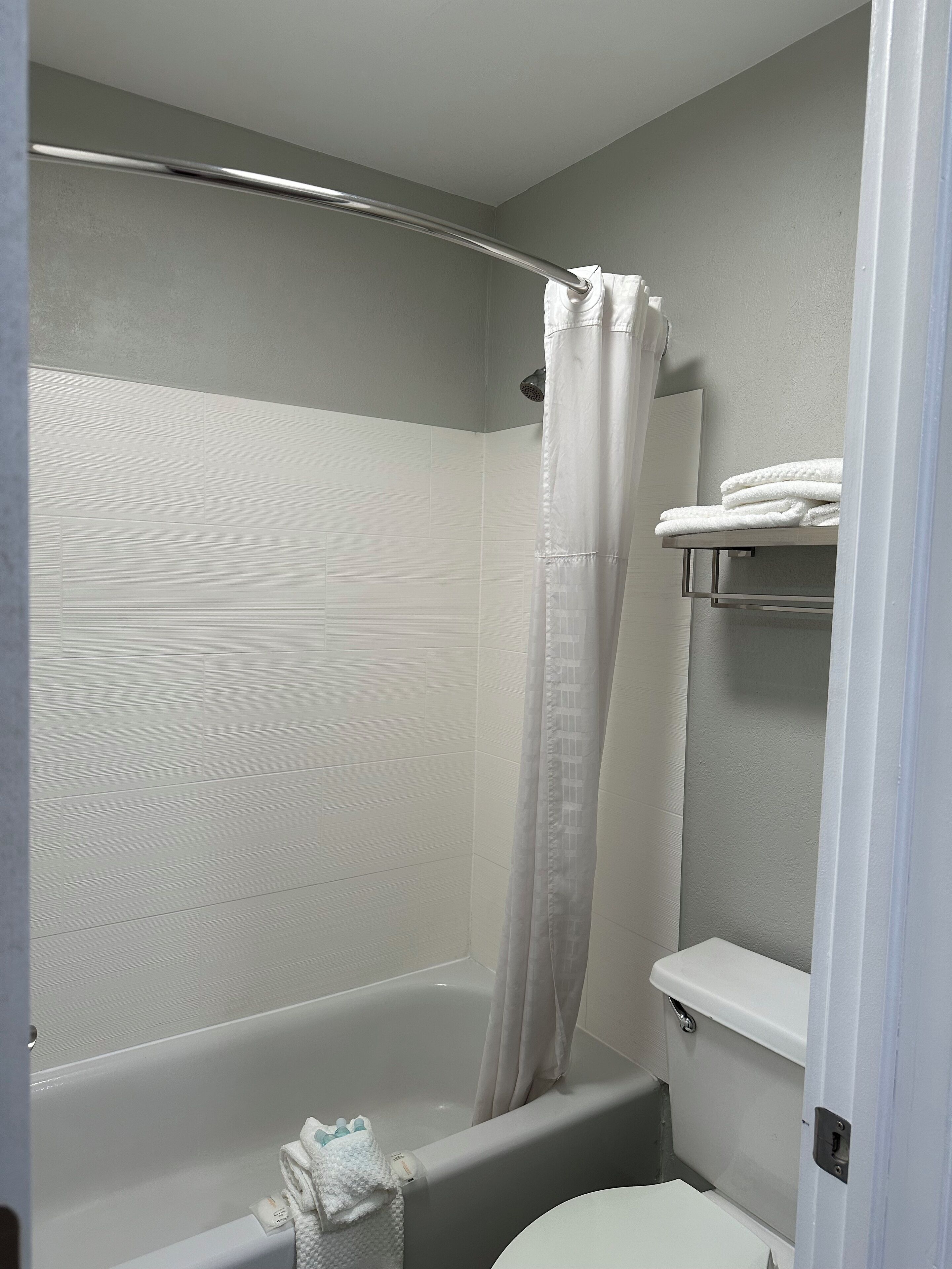 A bathroom with a shower, toilet, and a towel rack.