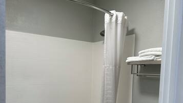 Un baño con ducha, inodoro y perchero para toallas.