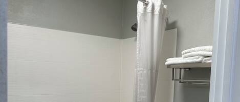 A bathroom with a shower, toilet, and a towel rack.