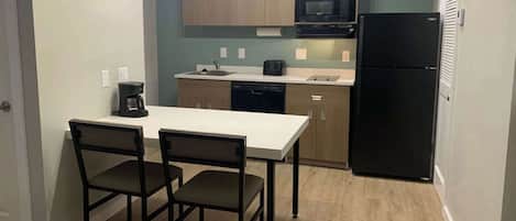 Kitchen area with a countertop, microwave, refrigerator, coffee maker, and toaster.