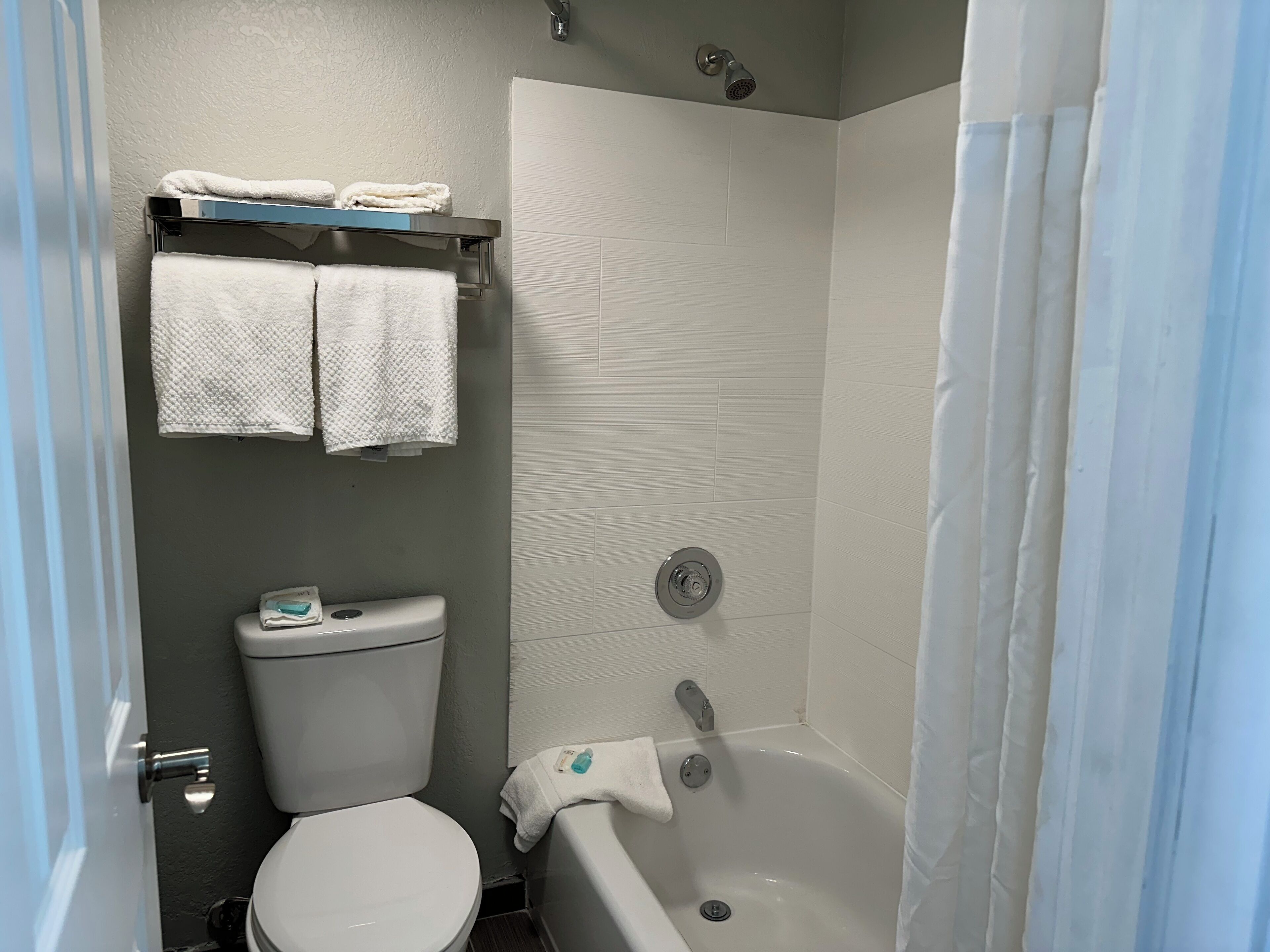 A bathroom with a toilet, a shower, and a bathtub. There are towels hanging on a rack above the toilet.