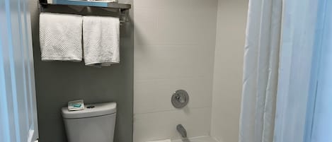 A bathroom with a toilet, a shower, and a bathtub. There are towels hanging on a rack above the toilet.