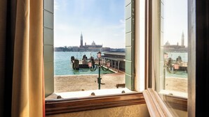 A view from a window overlooking a waterfront with boats and a historic building in the background. - Hotel Metropole Venezia (Venice)