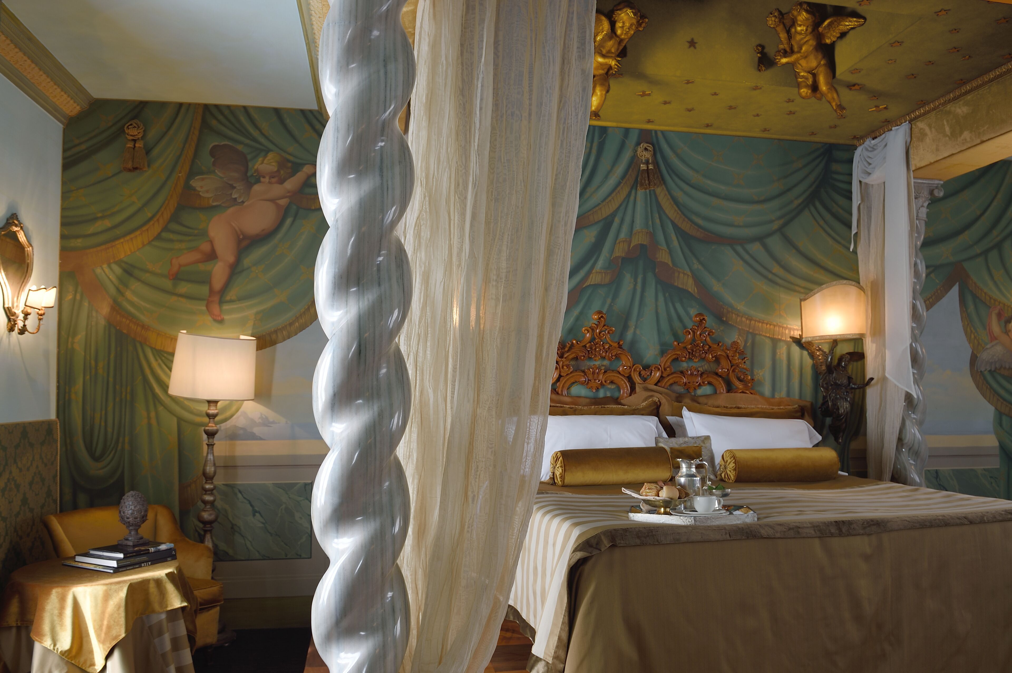 A luxurious bedroom with a canopy bed, ornate ceiling artwork, and classic decor.