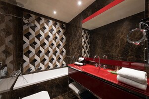 A modern bathroom with a red sink, a large mirror, and a shower.
