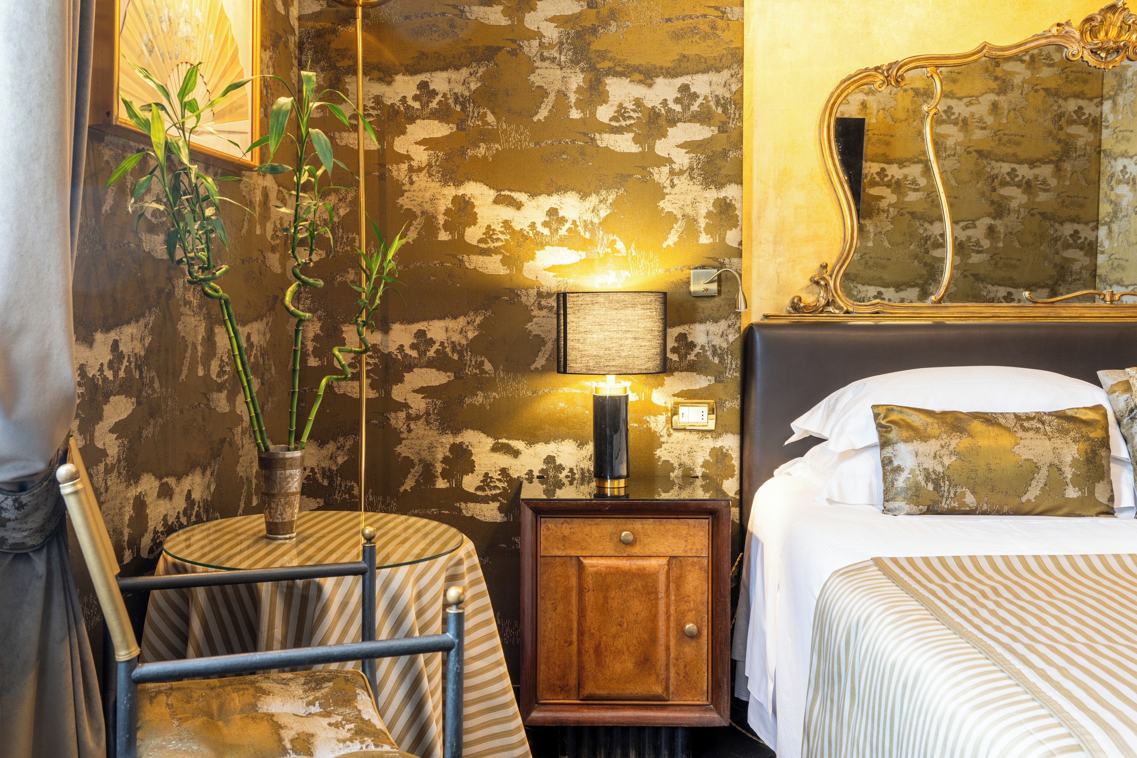 A hotel room with a bed, bedside table, lamp, and a wall with a textured pattern.