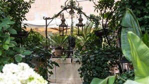 A garden area with a stone bench, potted plants, and hanging lanterns. - Hotel Metropole Venezia (Venice)
