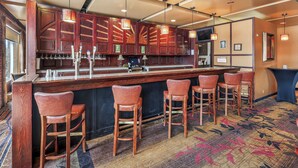 Una zona de bar con armarios de madera, taburetes y lámparas colgantes.
