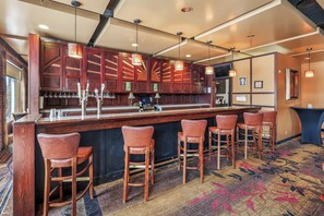Una zona de bar con armarios de madera, taburetes y lámparas colgantes.