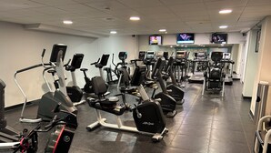 Un gimnasio con varias máquinas de cardio, incluyendo cintas de correr y bicicletas estáticas, dispuestas en filas.