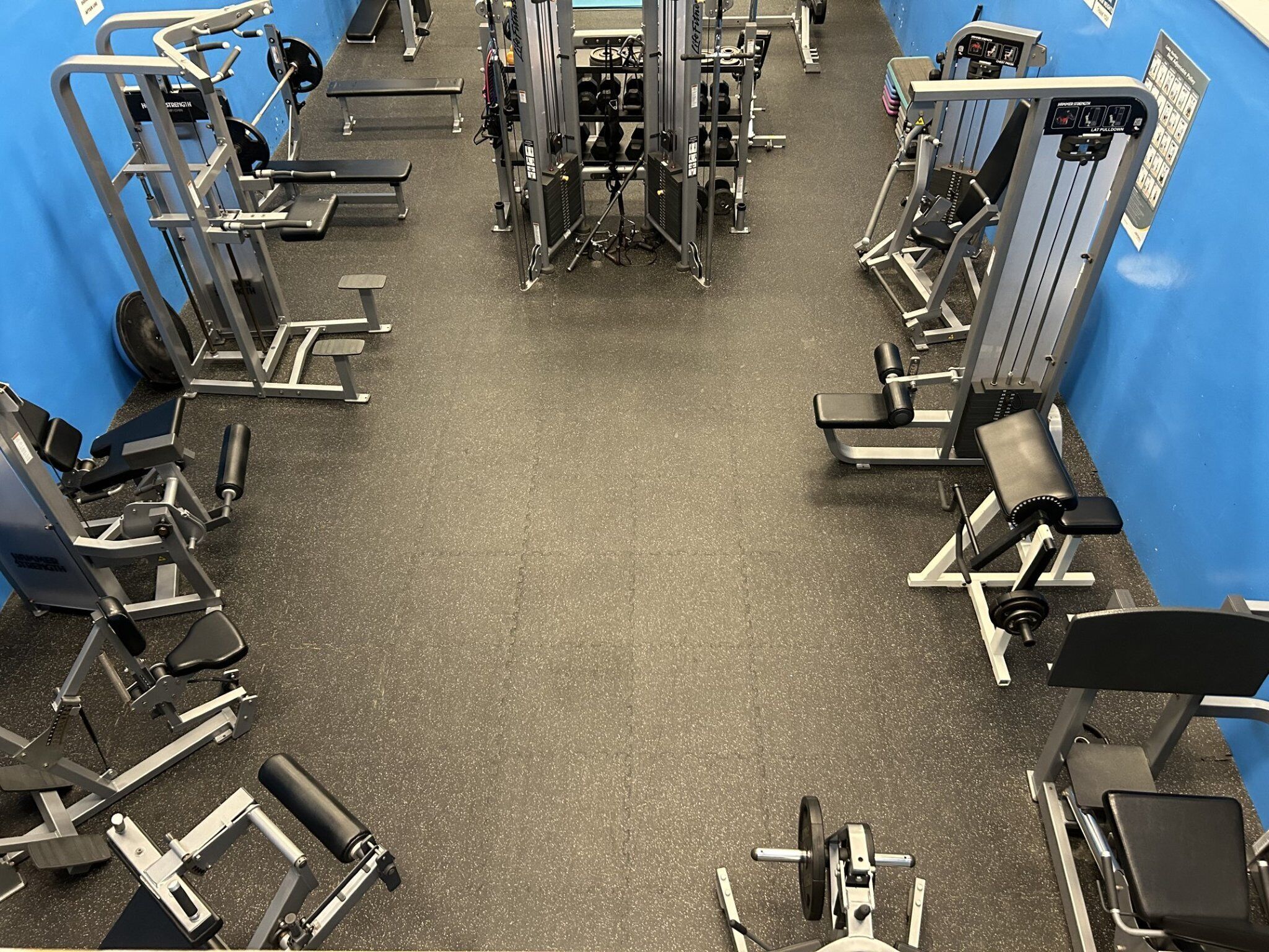 Une salle de sport équipée de divers appareils d’exercice, de bancs et d’haltères.