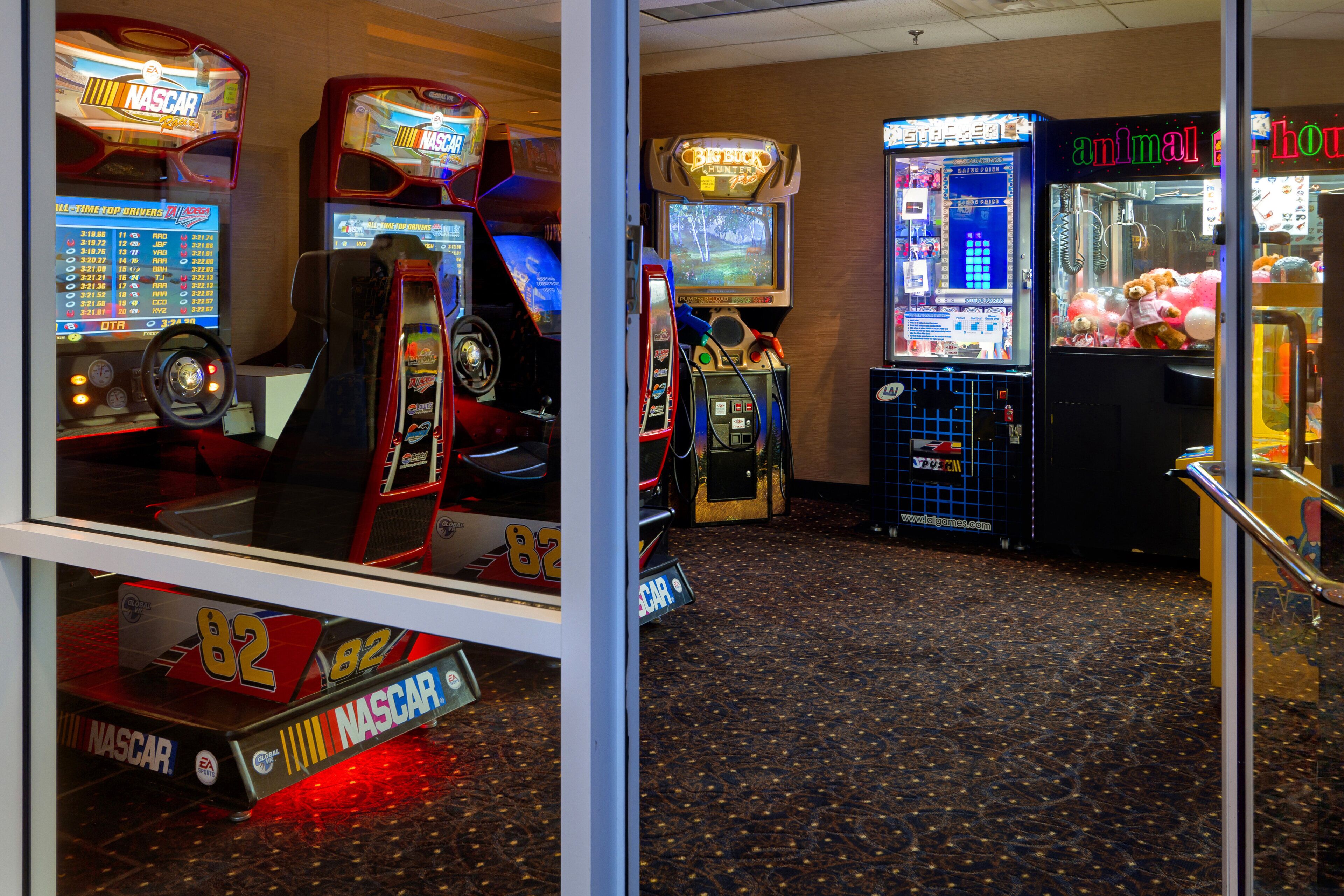Una fila de juegos de arcade, incluyendo un juego de carreras de NASCAR, un juego de Big Buck Hunter y una máquina con garra.