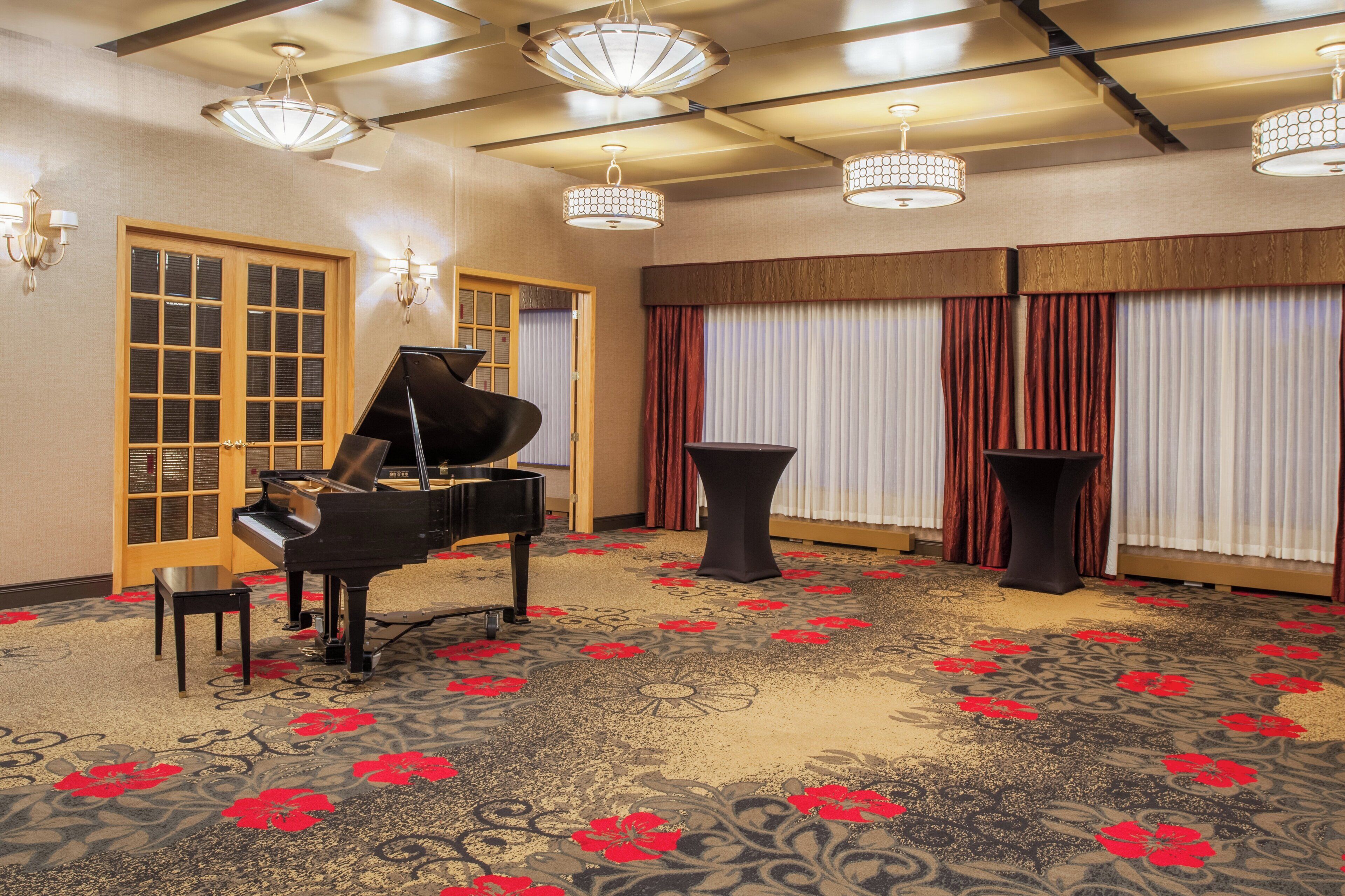 Una habitación con un piano de cola, una mesa y una alfombra estampada con motivos florales.