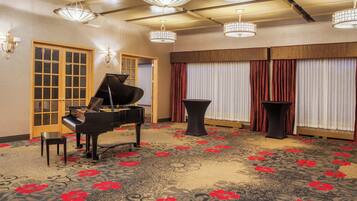 Una habitación con un piano de cola, una mesa y una alfombra estampada con motivos florales.