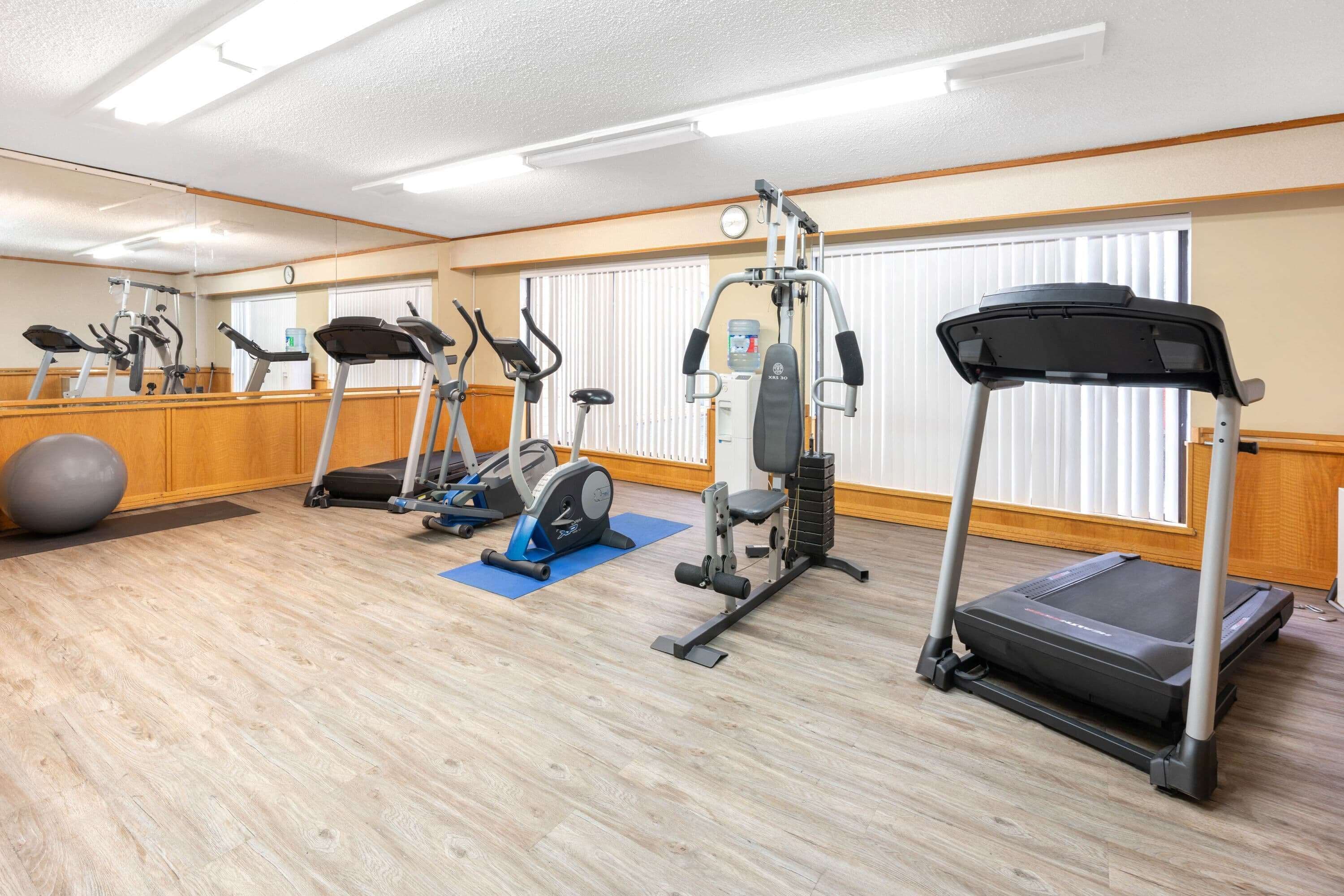 Een fitnessruimte met loopbanden, elliptische trainers en een roeimachine.