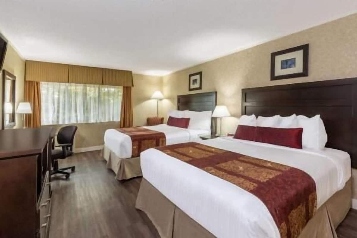 Ein Hotelzimmer mit zwei Betten, einem Schreibtisch und einem Stuhl.