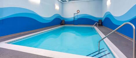 An indoor swimming pool with wave-patterned walls and a clock on the wall.