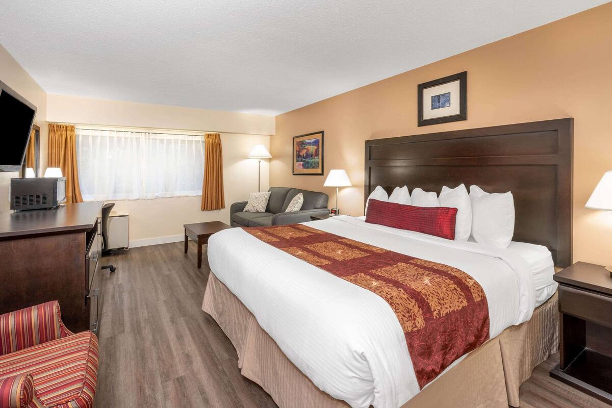 Ein Hotelzimmer mit einem großen Bett, einem Schreibtisch, einem Stuhl und einem Fernseher.