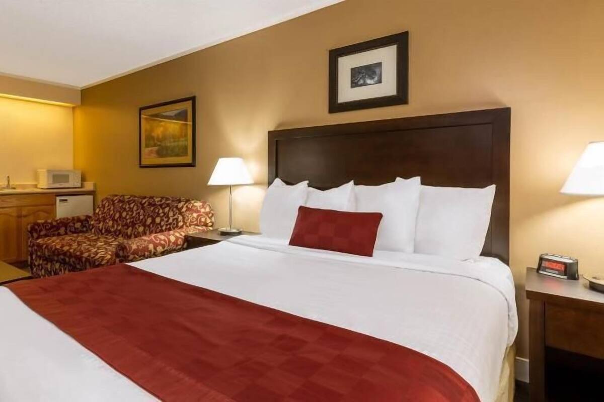 Ein Hotelzimmer mit einem Bett, einem Schreibtisch, einem Stuhl und einer Lampe.