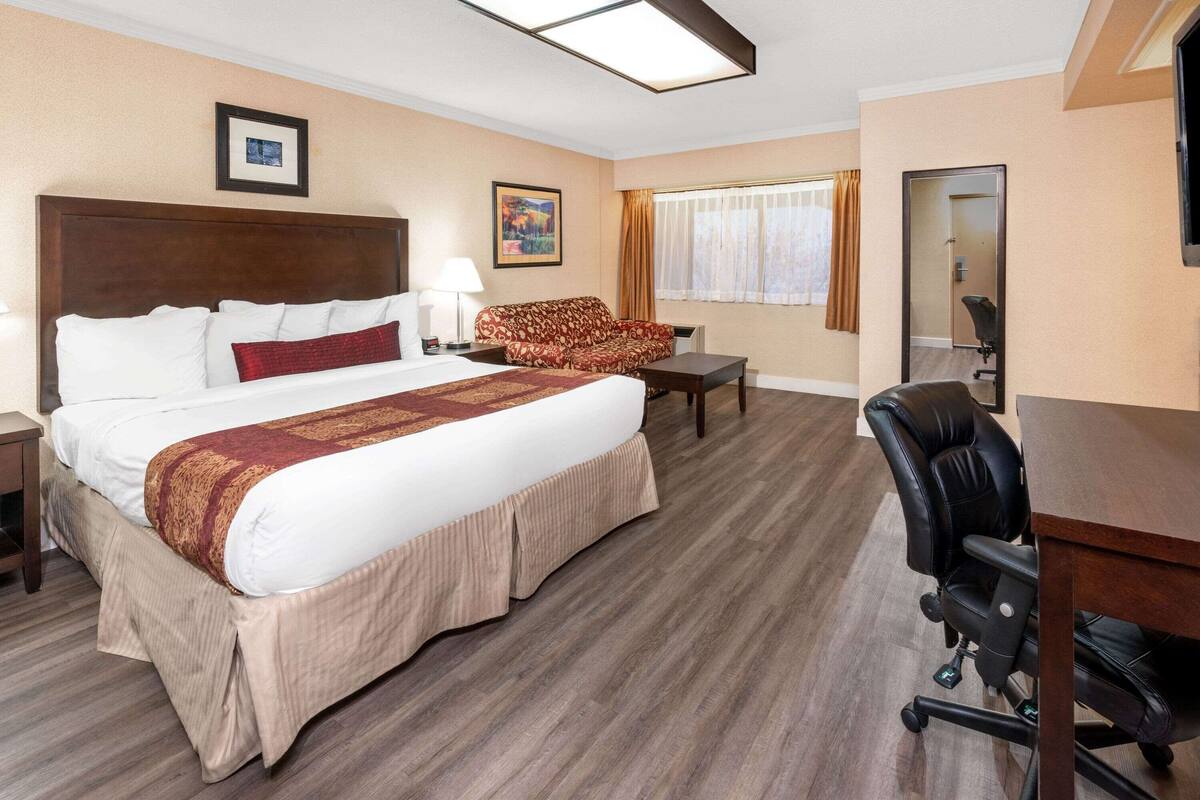 Ein Hotelzimmer mit einem großen Bett, einer Couch, einem Schreibtisch und einem Sessel.
