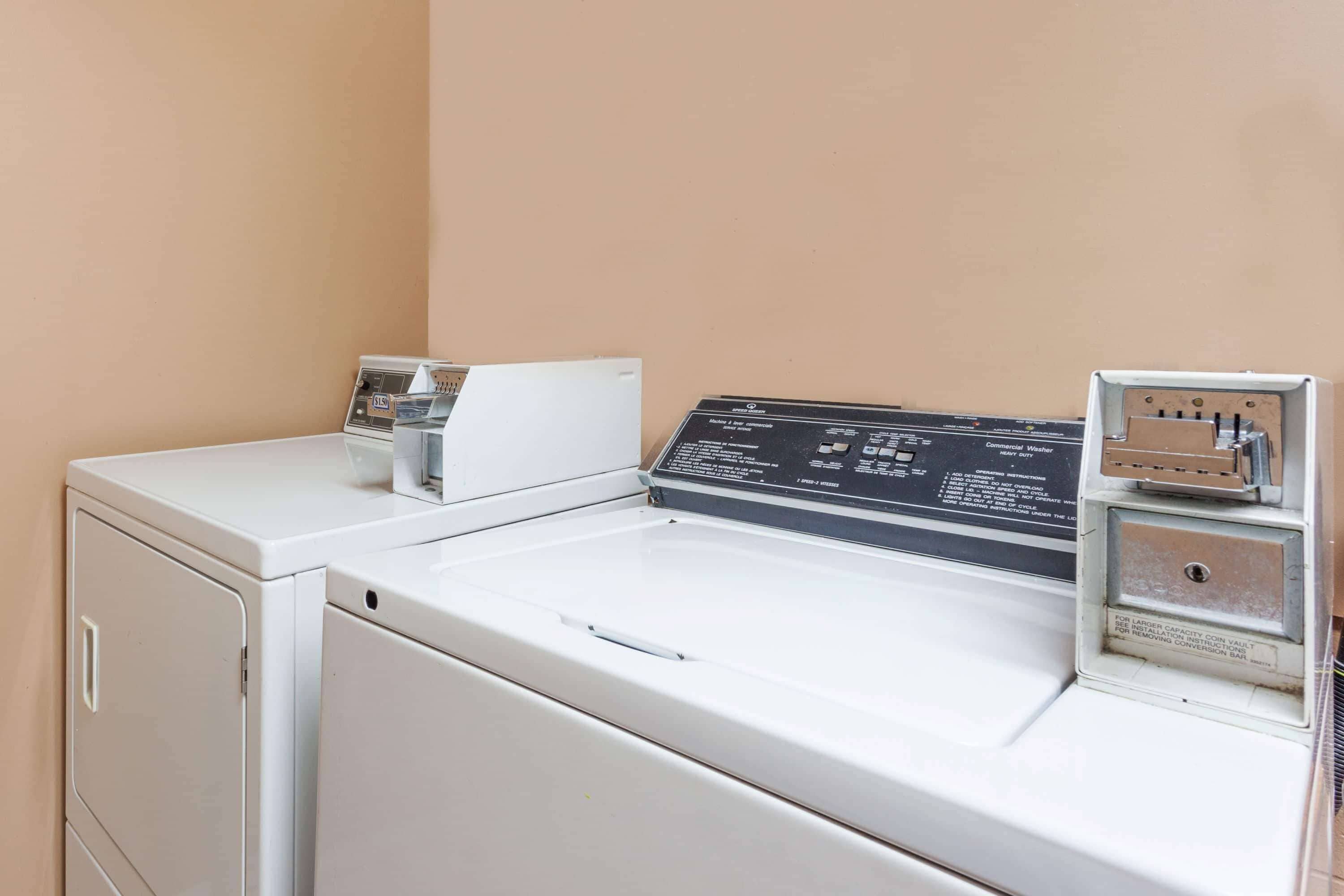 A laundry area with a front-loading washer and dryer, a control panel, and a coin-operated dryer.