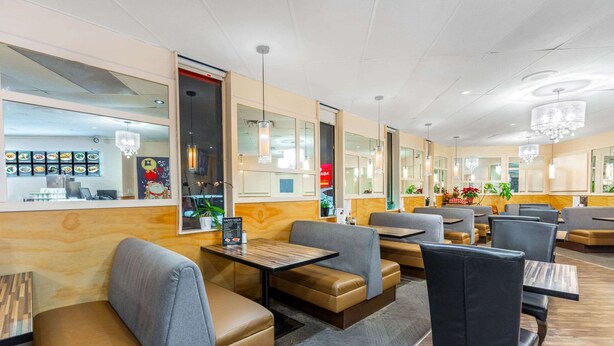 Un restaurante moderno con asientos tipo cabina, mesas de madera e iluminación colgante.