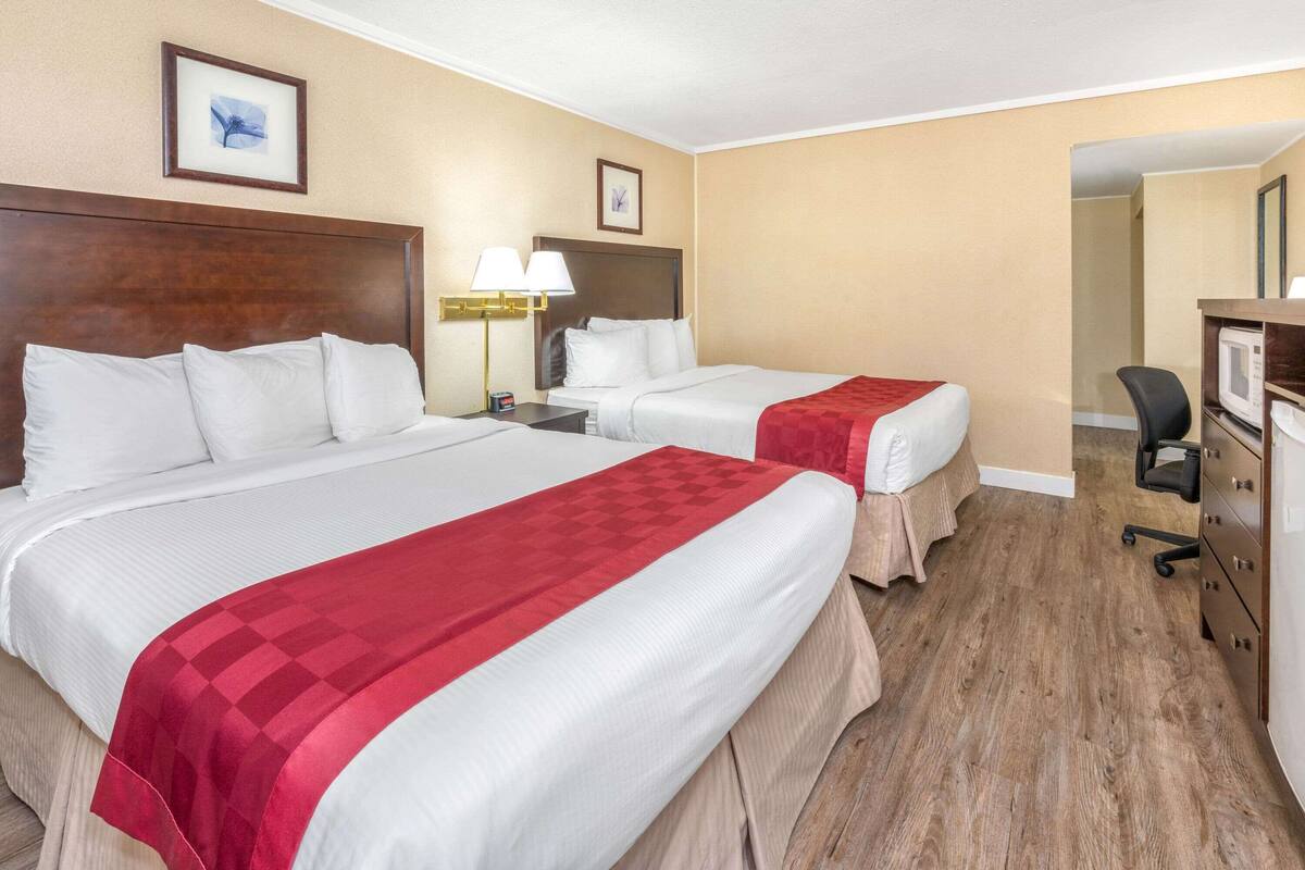 Ein Hotelzimmer mit zwei Betten, einem Schreibtisch, einem Stuhl und einem Fernseher.