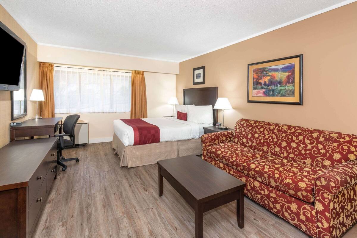Ein Hotelzimmer mit Bett, Sofa, Schreibtisch und Fernseher.