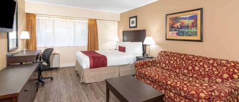 Une chambre d’hôtel avec un lit, un canapé, un bureau et une télévision.