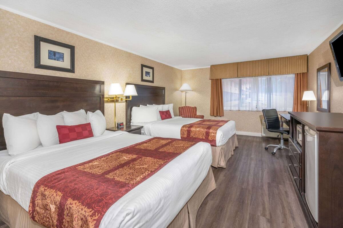 Ein Hotelzimmer mit zwei Betten, einem Schreibtisch, einem Stuhl und einem Fernseher.