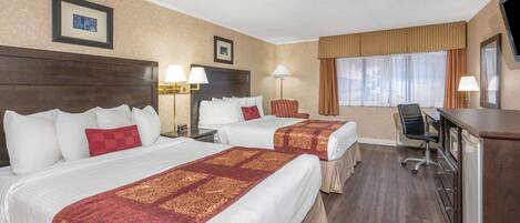 Habitación de hotel con dos camas, un escritorio, una silla y un televisor.