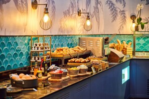 A breakfast buffet with various food items and a decorative wall with floral patterns.