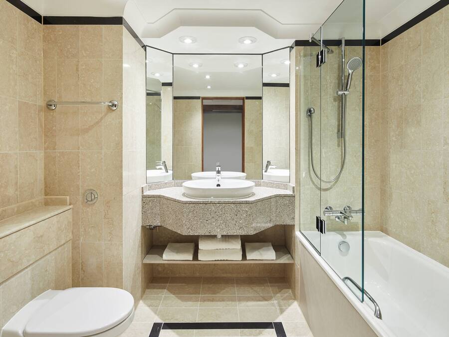 A modern bathroom with a glass-enclosed shower, a bathtub, a toilet, and a vanity with a sink and mirror.