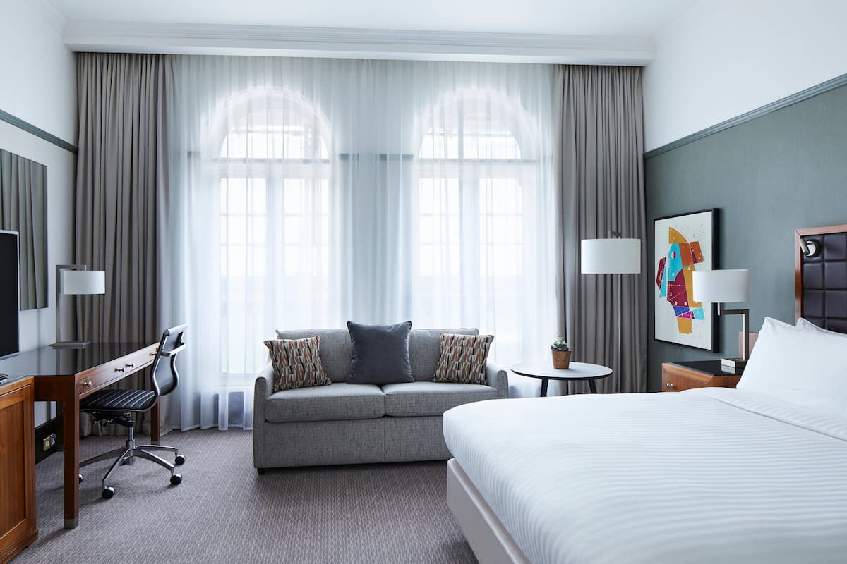 A hotel room with a bed, a sofa, a desk, and a TV.