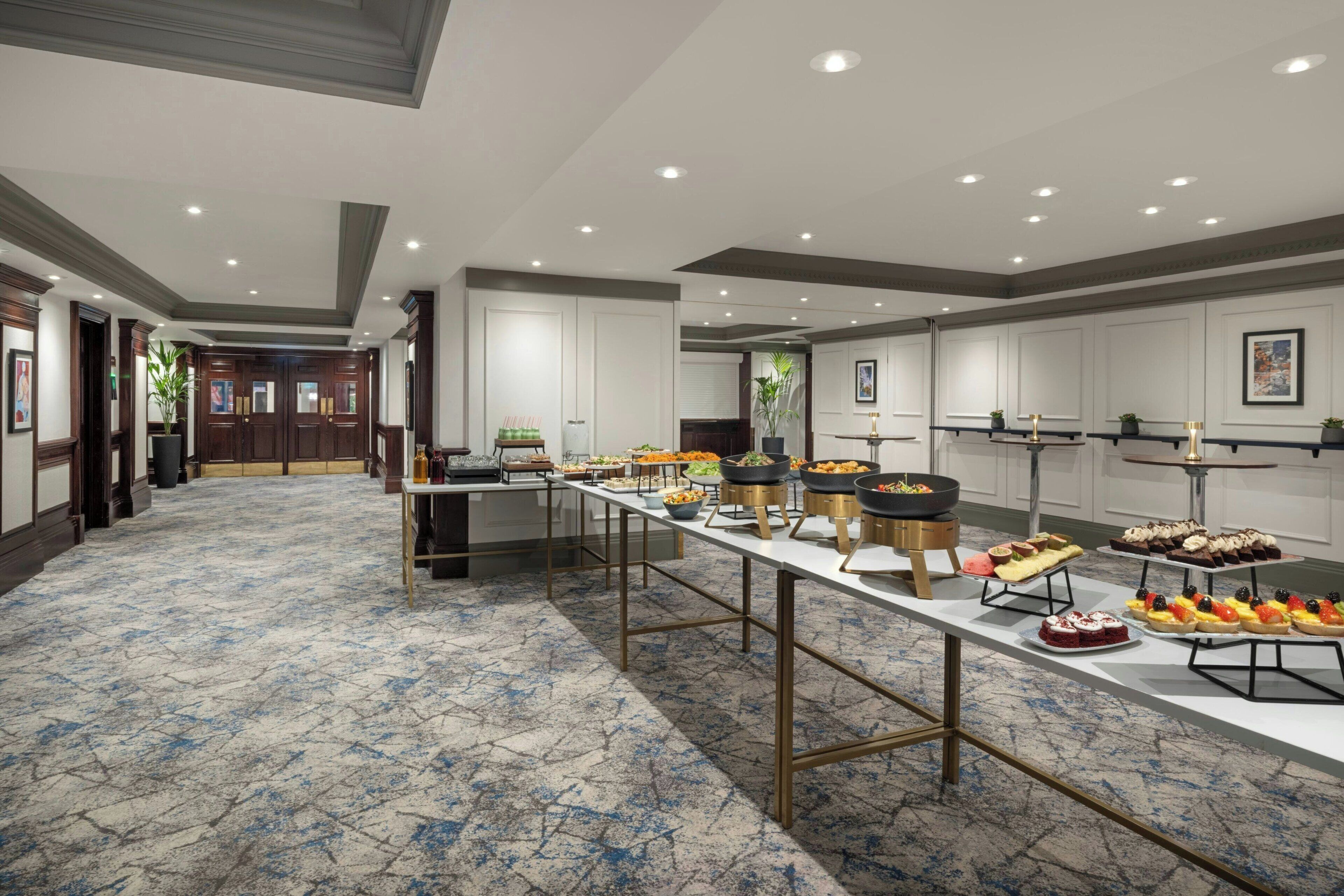 A spacious room with a long buffet table displaying various food items.