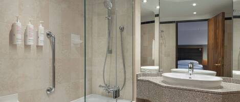 Un baño moderno con ducha de vidrio, una bañera blanca y un lavamanos con encimera de granito.