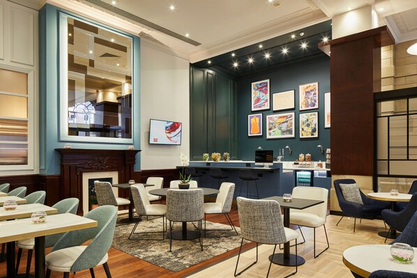 A modern dining area with round tables and chairs, a bar with artwork, and a fireplace. - Leeds Marriott Hotel (Leeds)